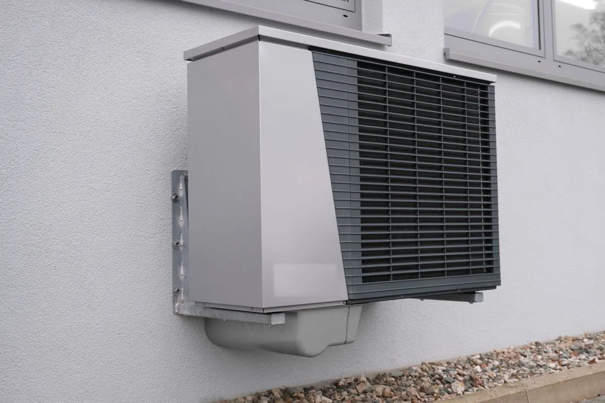 Illustrative residential outdoor heat pump installation beside a home's windows