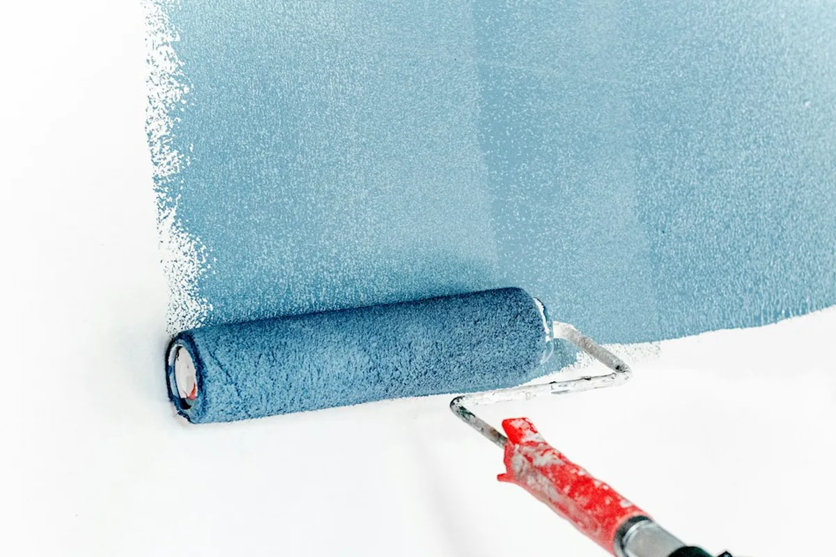 Illustrative repaint work: an extended roller applying blue paint across a white wall