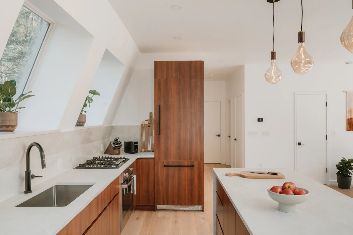 Illustrative finished kitchen with fitted wood cabinetry, stone counters and island